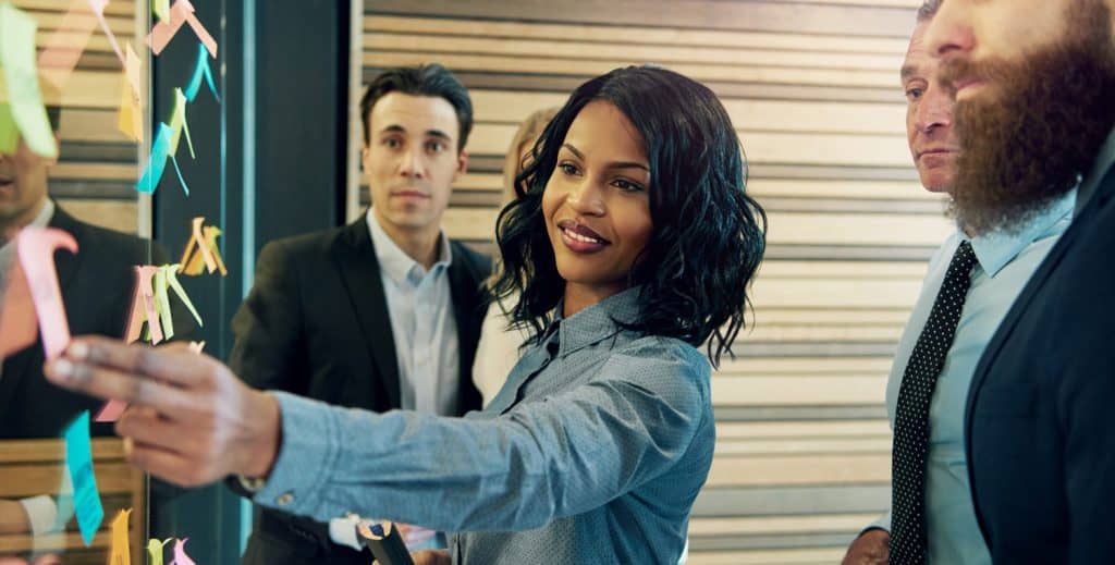 Creative group of business people brainstorming putting sticky notes on glass wall in office