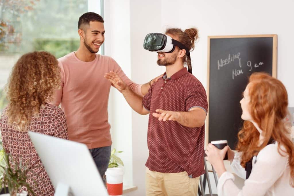 Man with virtual reality glasses testing new product during team meeting in the office