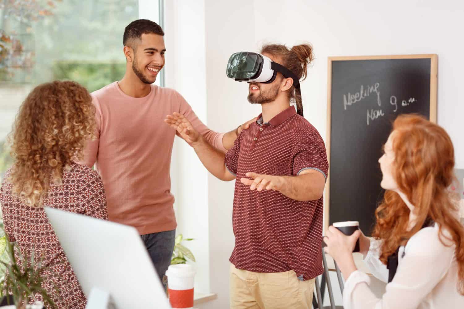 Man with virtual reality glasses testing new product during team meeting in the office