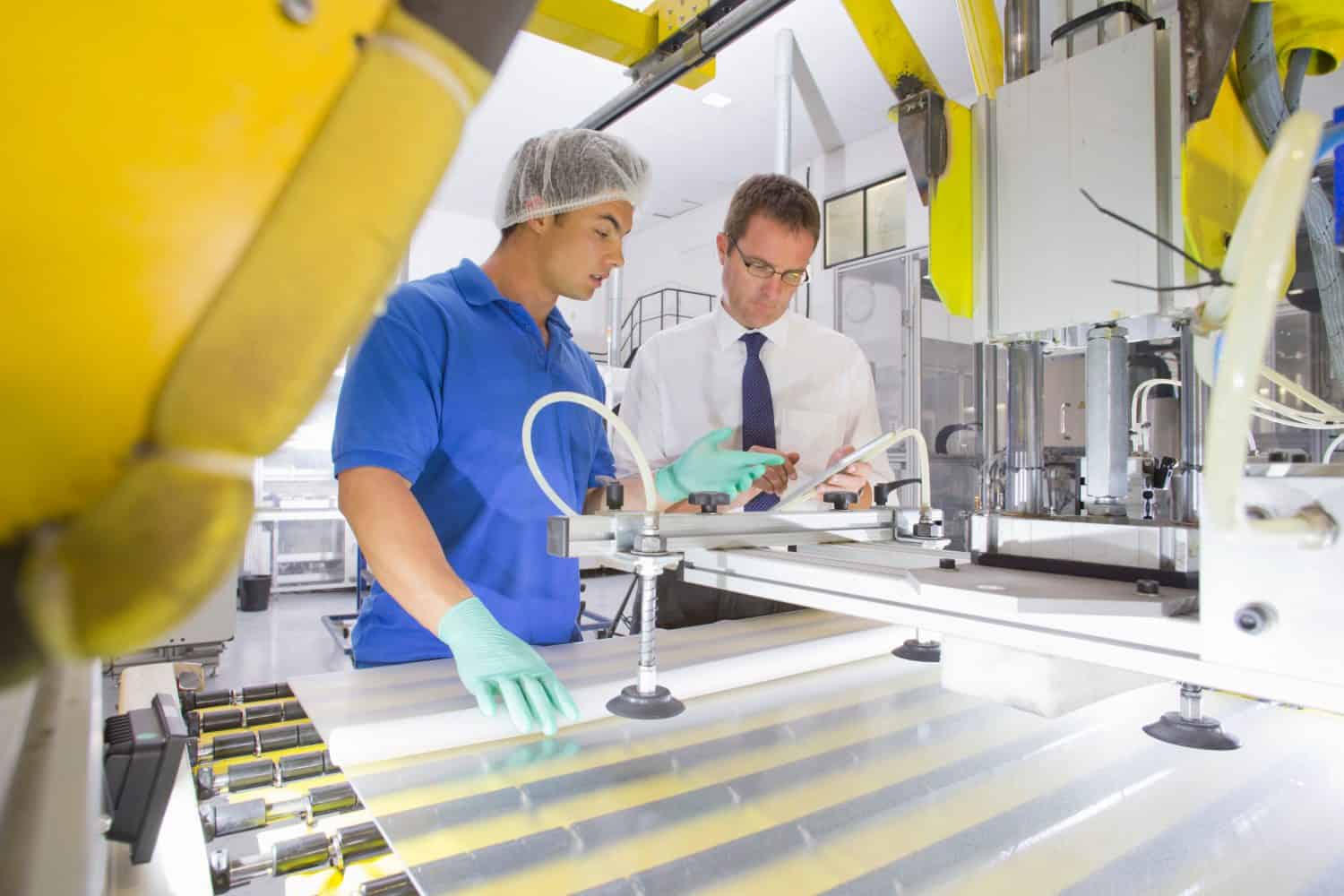 Side shot of an Engineer and a Technician working on coating glass for use in production of solar panels