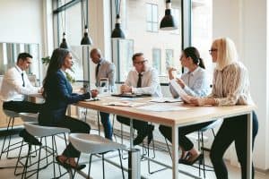 Focused group of diverse businesspeople discussing paperwork together during a meeting around a table in a modern office