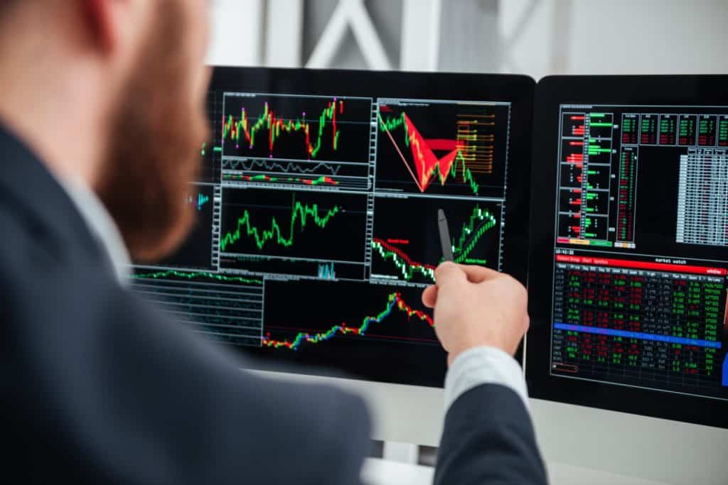 Closeup of businessman pointing on monitor of computer with charts and graphs in office