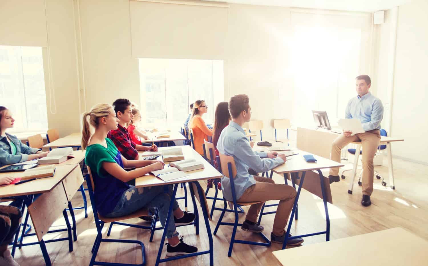 education, school and people concept - group of happy students and teacher with papers or tests