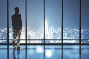 Businessman standing in contemporary office interior and looking to night city. Success, vision and future concept. Multiexposure