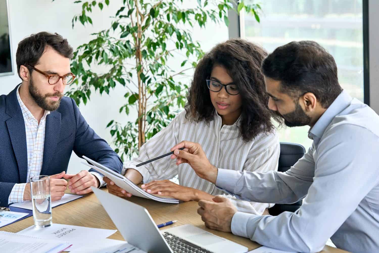 International executive business people team negotiating financial research report at boardroom meeting table. Multiracial team doing paperwork for developing business strategy plan in modern office.