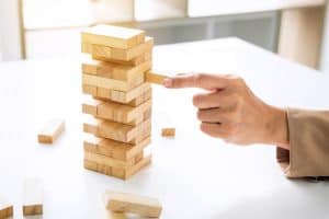 Alternative risk plan and strategy to growth profit in business, Young intelligent business woman playing the wood game, hands of executive placing wood block on the tower.