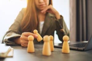 Businesswoman leader choosing wooden people from a group of employees in office